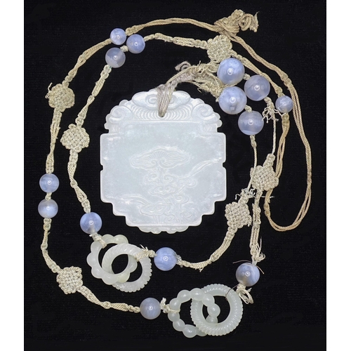 799 - A Chinese celadon jade and blue agate necklace, the pendant of shaped oval form, carved in low relie... 