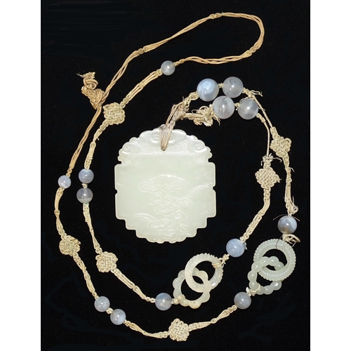 799 - A Chinese celadon jade and blue agate necklace, the pendant of shaped oval form, carved in low relie... 