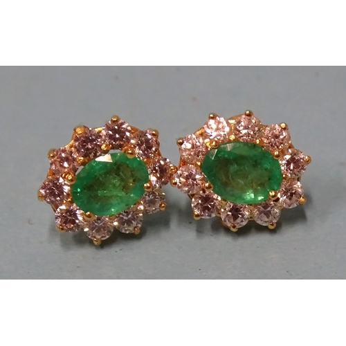 827 - A pair of emerald and white stone cluster ear studs, each claw-set an oval-cut emerald of approximat... 