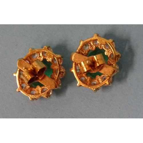 827 - A pair of emerald and white stone cluster ear studs, each claw-set an oval-cut emerald of approximat... 