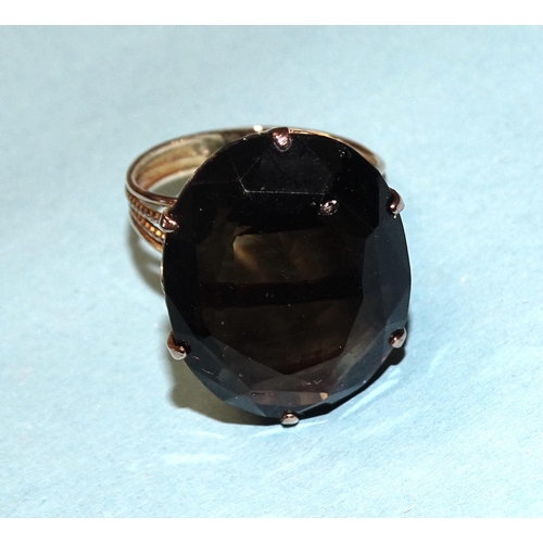 829 - A dress ring claw-set a large oval smoky quartz, in unmarked yellow metal mount, size Q½, 8.5... 