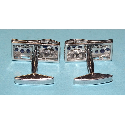 852 - A pair of 18ct white gold cufflinks, each set a wavy line of six round-cut sapphires and one brillia... 