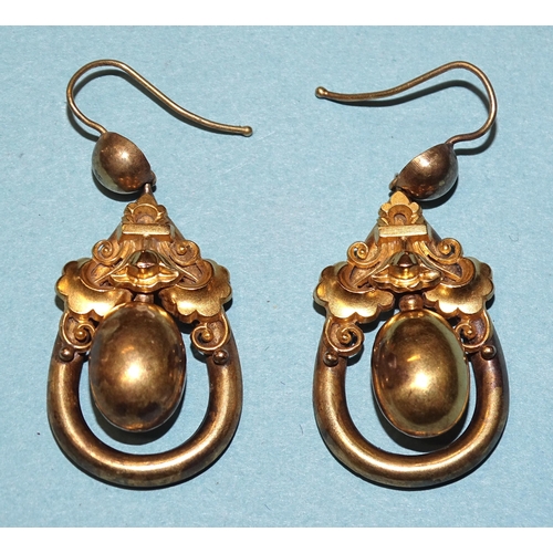 854 - A pair of Victorian yellow metal earrings of drop form, with oval bead suspended within hollow frame... 