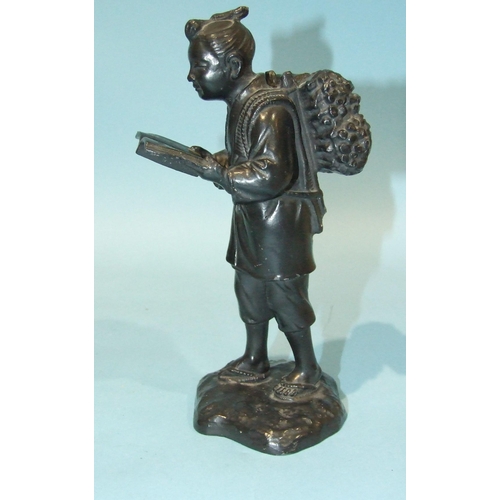 158 - A Japanese bronzed metal figure of a man carrying corn sheafs and reading a book, 19cm high.... 