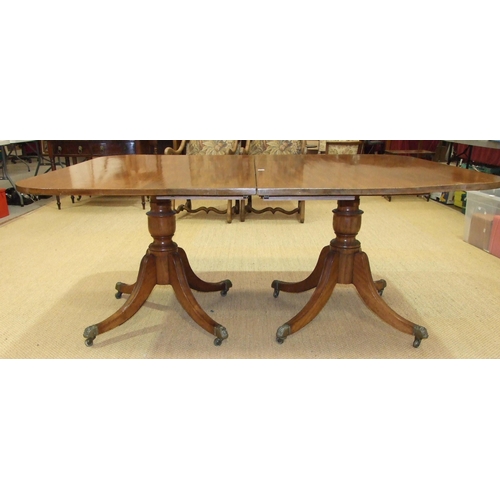38 - A Georgian mahogany twin-pillar dining table, the top including two spare leaves supported on turned... 
