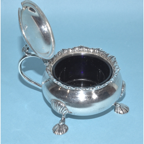 12 - An Edwardian silver mustard of circular form, with gadrooned rim and hinged lid, on three hoof feet,... 