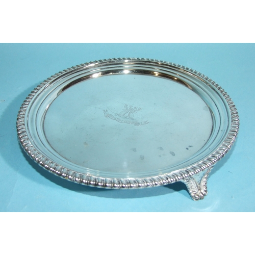 34 - A George III circular silver salver with gadrooned border, on tapering scroll feet, with engraved ce... 