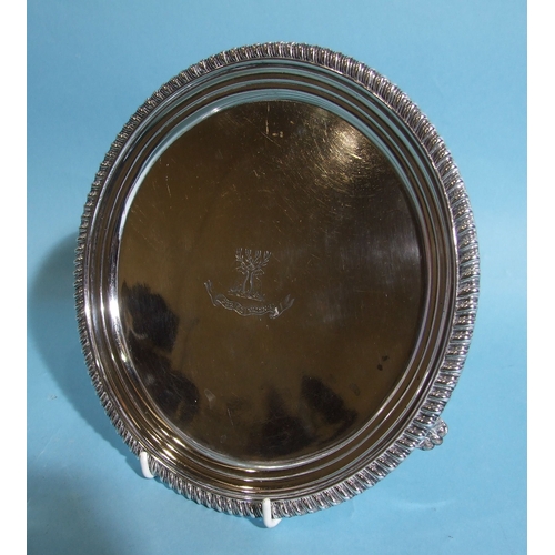 34 - A George III circular silver salver with gadrooned border, on tapering scroll feet, with engraved ce... 