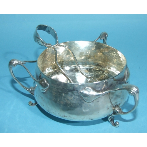 45 - An Edwardian silver circular sugar bowl in the Art Nouveau style, having three tendril-shaped handle... 