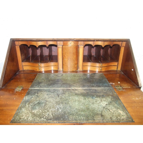 5 - A George III mahogany bureau, the fall front enclosing the serpentine-shaped inlaid satinwood fitmen... 