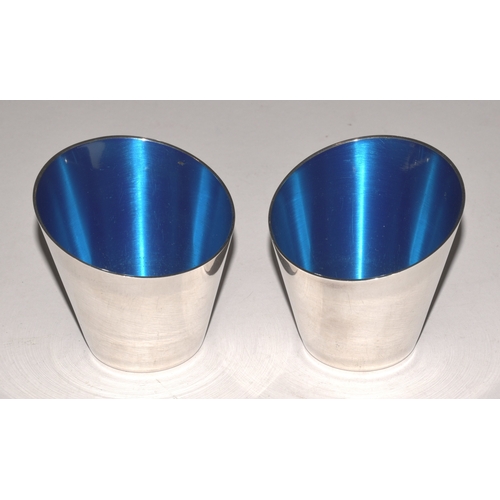 A pair of Danish plated asymmetric cups with blue enamel interiors, 6.5cm maximum height, 6.7cm maximum width, (2).
