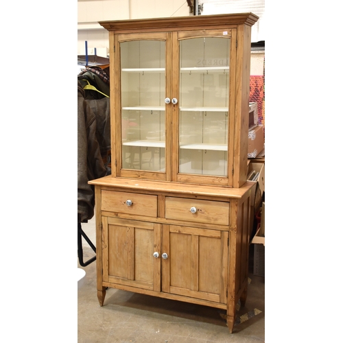 11 - A stripped pine dresser, the cornice above a pair of glazed doors, two drawers and two cupboard door... 