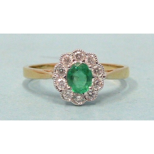 303 - An emerald and diamond cluster ring, claw-set an oval emerald within a border of ten brilliant-cut d... 