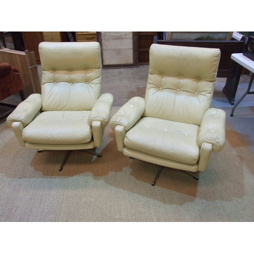 28 - A pair of 1960's/70's generously-seated and buttoned cream leather swivel chairs on five-legged chro... 