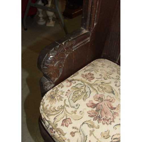 34 - An antique small oak pew of panelled construction, with leaf-carved arms, 116cm wide, 90cm high.... 