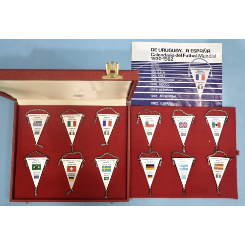 52 - A set of twelve white metal football pennants commemorating the World Cup hosts and winners 1930-198... 