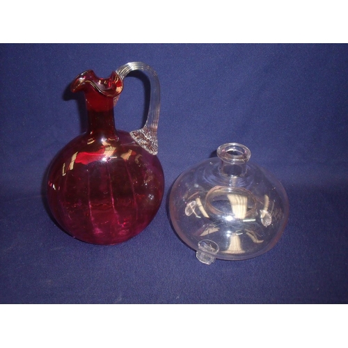 26 - Cranberry glass moon shaped jug with clear glass handle and flared rim (20cm high) and a clear glass... 