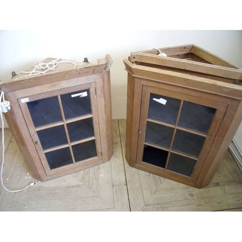 419 - Pair of light oak wall mounted corned cupboards enclosed by single glazed doors