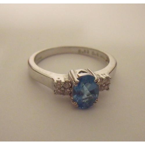 106 - 9ct white gold ring set with pale blue stone with four diamond chips to each shoulder