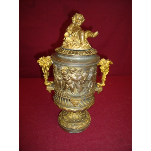 101 - Highly ornate cast & gilt metal urn with lift off lid crested with a figure of a Bacchus type cherub... 