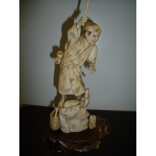 17 - 19th/20th C Japanese carved ivory figure of a fisherman on rock, on hardwood base (26cm high)