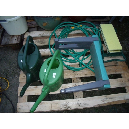 93 - Two plastic watering cans, a hose and a pair of garden kneelers
