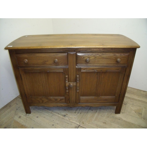 334 - Ercol medium coloured elm 4ft sideboard with two drawers above two panelled cupboard doors