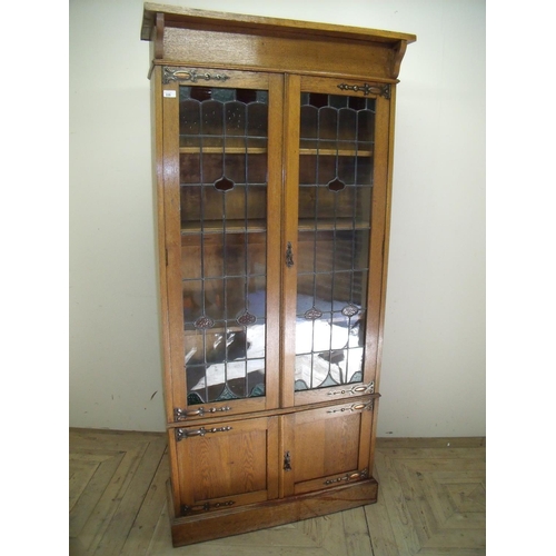 335 - Early 20th C golden oak cabinet with two upper lead glazed cupboard doors above two panelled doors (... 