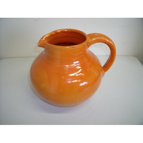 46 - Large orange glazed Studio pottery jug, the base with impressed marks KW (24cm high)