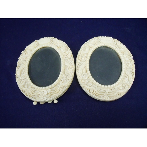 72 - A pair of 19th/20th C Chinese carved ivory oval picture frames, the border carved with various figur... 