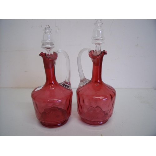 49 - Pair of similar cranberry and clear glass bottle decanters with loop handles