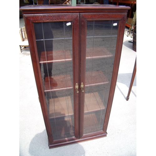 423 - Modern mahogany effect cabinet enclosed by two glazed doors (63cm x 33cm x 128cm)