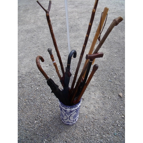 93 - Blue & white ceramic stick stand containing a selection of various walking sticks, umbrellas, thumb ... 