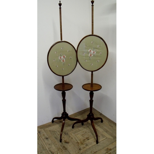256 - Pair of 19th/20th C mahogany pole screens with circular shelf under oval panels depicting floral nee... 