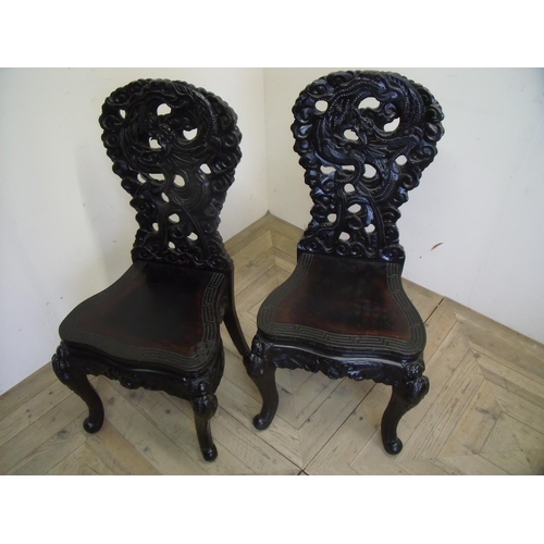 266 - Pair of black lacquered heavily carved oriental style dining chairs