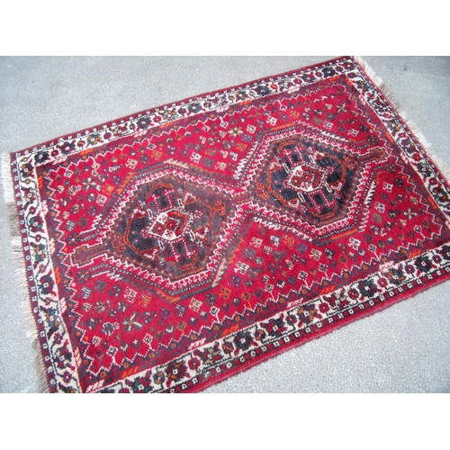 320 - 20th C Bokhara red ground rug with two central medallions and floral border (157cm x 103cm)