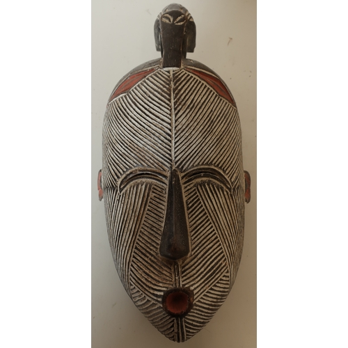 91 - Unusual carved wood face mask with white and red highlighted detail, crested with carved figure of a... 