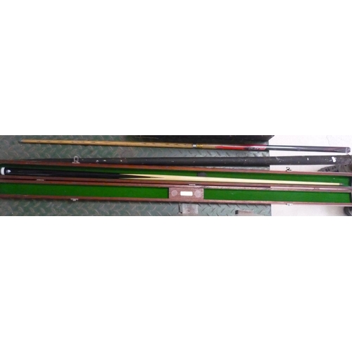 36 - Three snooker cues, one in vintage metal carrying case, one in wooden carrying case
