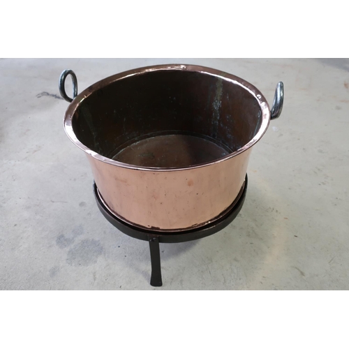 64 - Polished twin handled copper log bin on wrought metal stand (diameter 51cm, 48cm high)