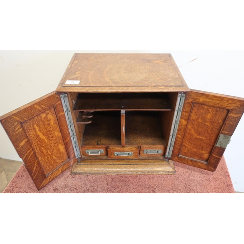 94 - Edwardian oak table/smokers cabinet enclosed by two panelled cupboard doors with fitted interior, in... 