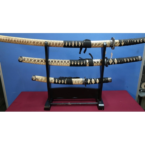52 - Set of three decorative Japanese style samurai swords with stand