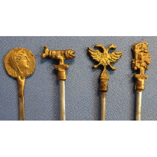 11 - Set of twelve meat skewers, the gilt metal tops with various crests, Roman style figures etc