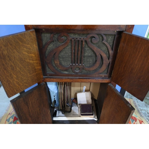 179 - Early 20th C oak cased gramophone with hinged top and four cupboard doors, with various records etc ... 