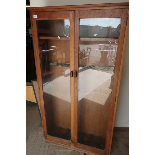 144 - Early to mid 20th C oak gun style cabinet enclosed by two glazed doors with internal shelf and gun r... 