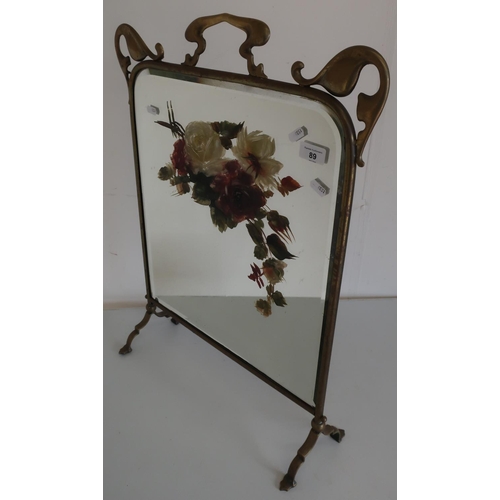 89 - Art Nouveau brass framed fire screen, the bevelled edge mirror panel with painted floral detail