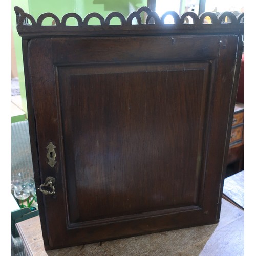 483 - George III oak wall cabinet with pierced arch frieze, and fielded panel door enclosing two shelves (... 