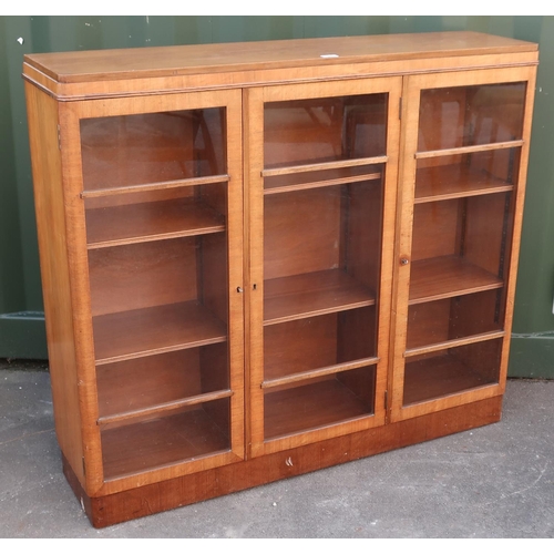 425 - 1940s walnut bookcase with three glazed doors and adjustable shelves on a plinth base (122cm x 108cm... 