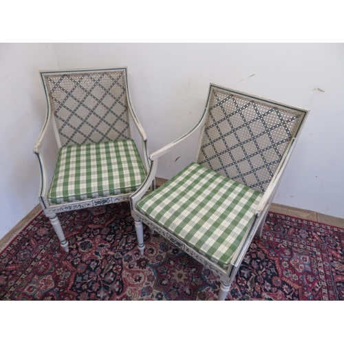 114 - Pair of Sheraton Revival cane seat open arm chairs, the white frames painted with foliage, and scrol... 