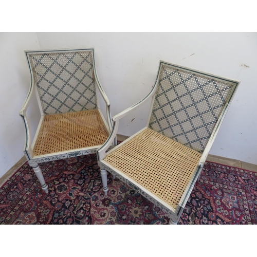 114 - Pair of Sheraton Revival cane seat open arm chairs, the white frames painted with foliage, and scrol... 