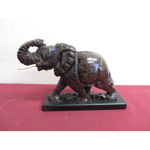 9 - Polished hardstone model of an elephant with bone tusks on a wooden plinth (H20cm)